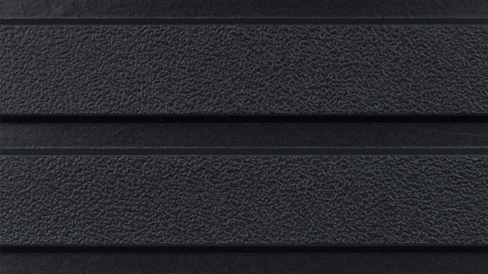 A close-up of a textured black surface with horizontal ridges. The material appears rough and matte, with two prominent grooves running across the image. The surface has a consistent pattern and uniform color.